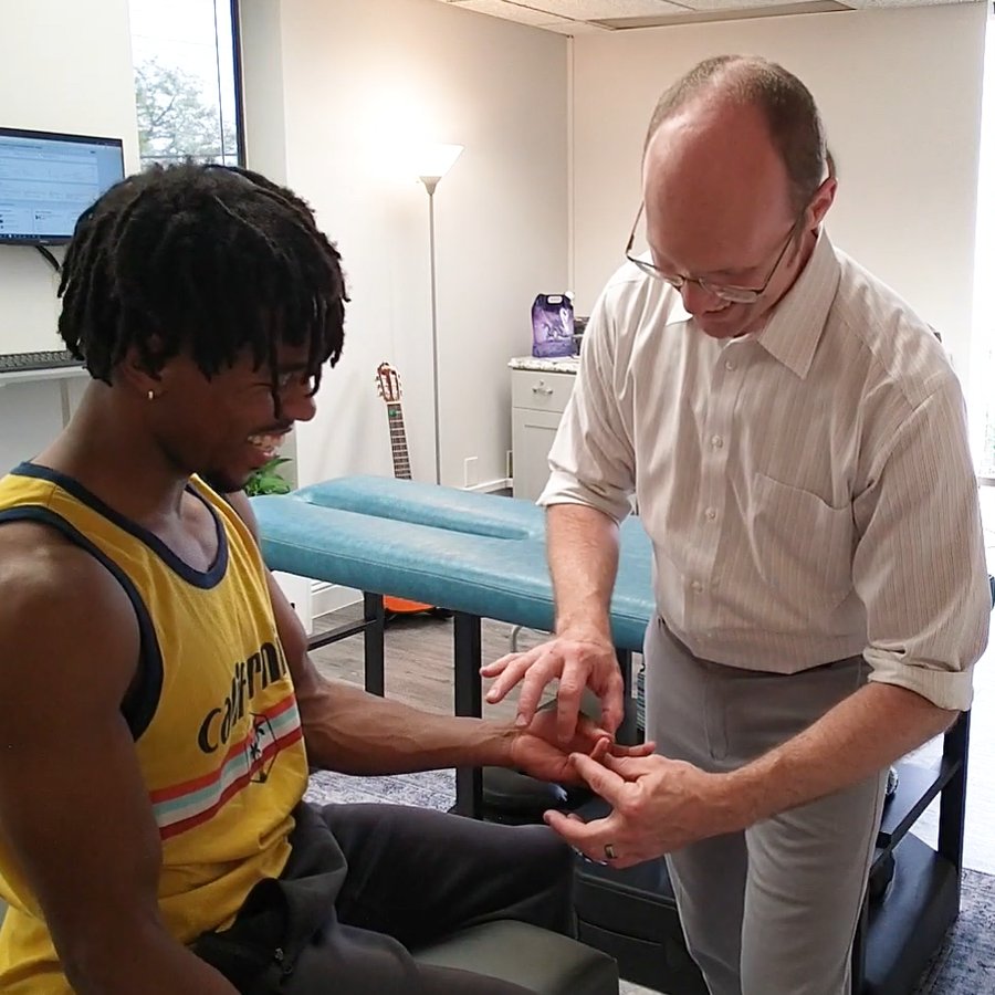 Dr. Jason performing a muscle test on a practice member's arm