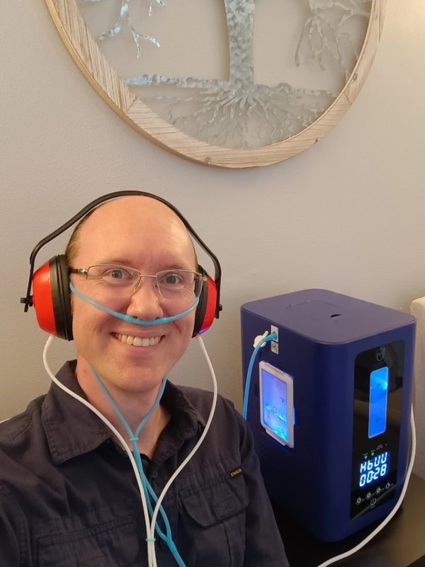 Dr. Jason wearing the hydrogen headset and nasal cannula beside the HydroHeal unit